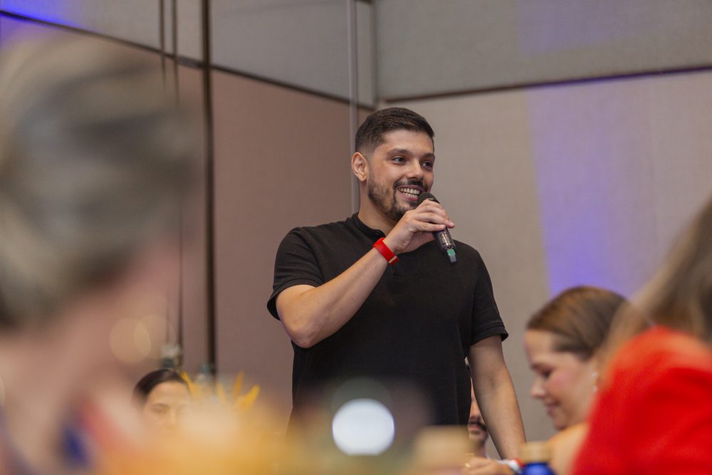 Victor Luporini com microfone, falando para a sala cheia da mentoria Nice