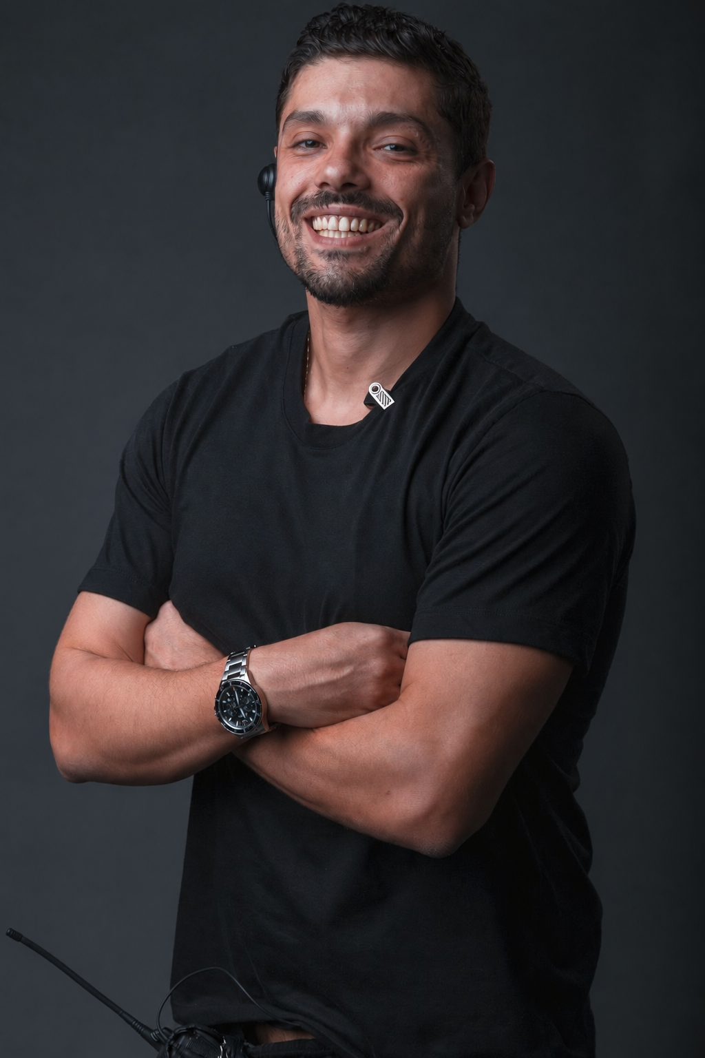 Victor Luporini em retrato de estúdio, braços cruzados, fundo escuro