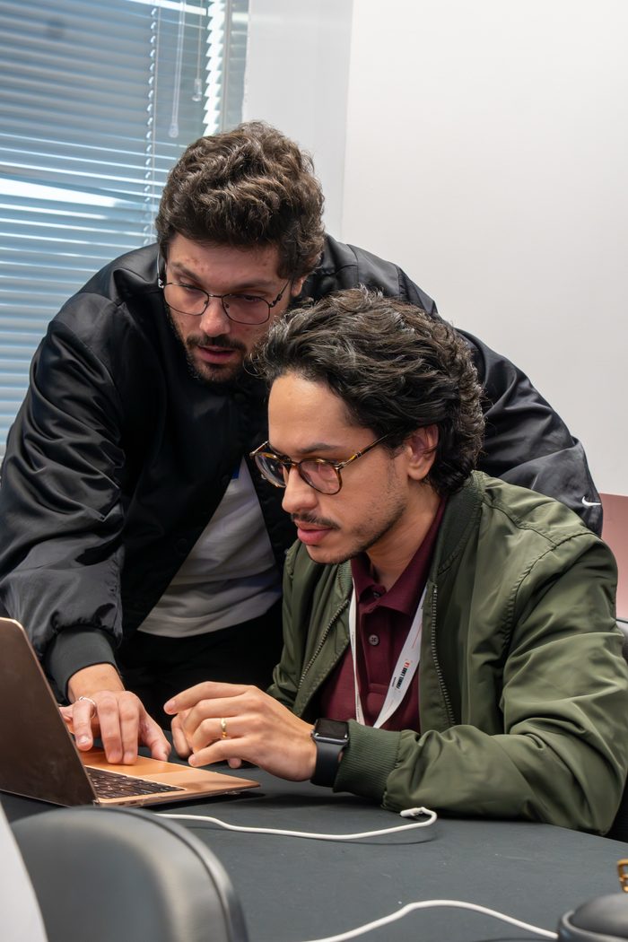 Victor Luporini ao lado de um participante, montando junto no computador